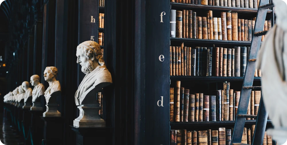 Marble busts lined up beside tall bookshelves in a historic library